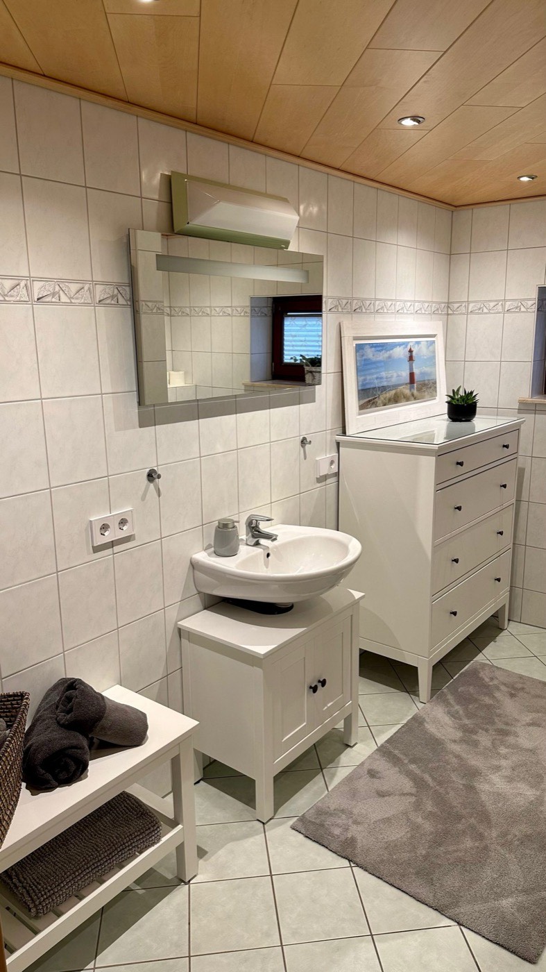Badezimmer mit Waschtisch, Spiegel und Kommode