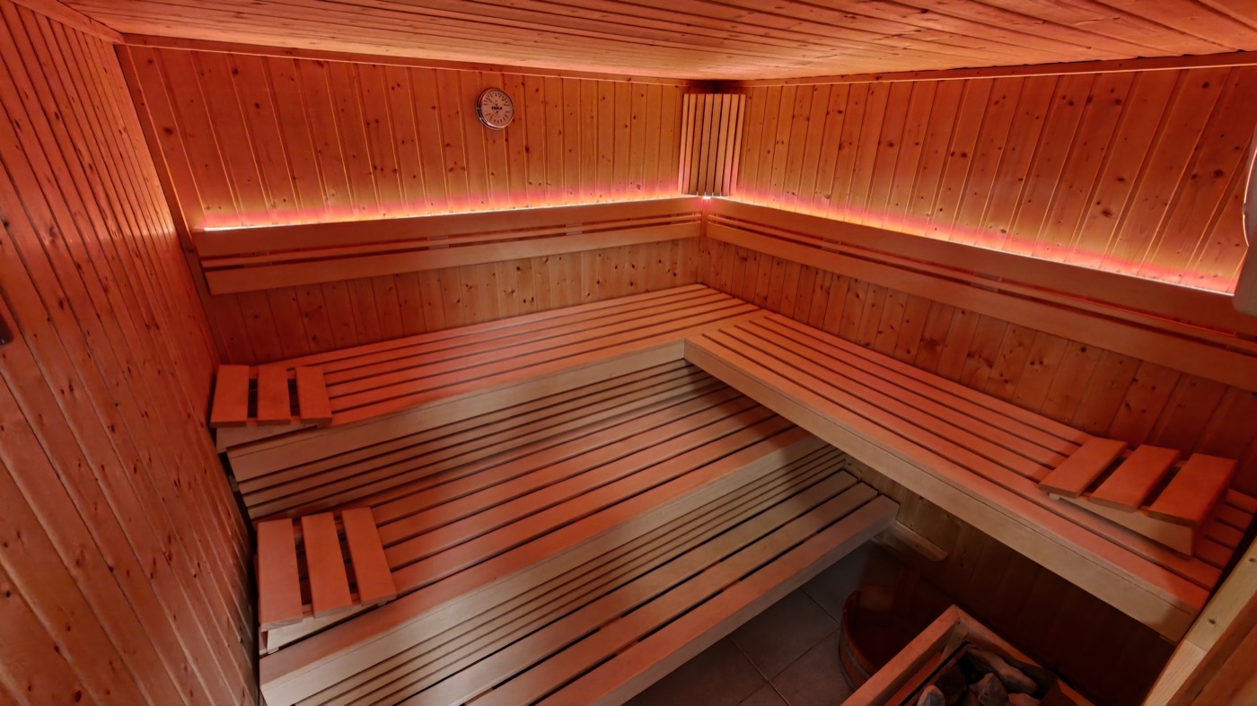 Innenansicht der finnischen Holzblocksauna mit zwei Sitzebenen und indirekter Beleuchtung